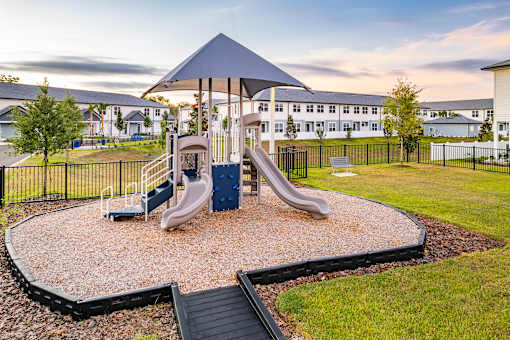A playground with a blue slide and a black canopy.