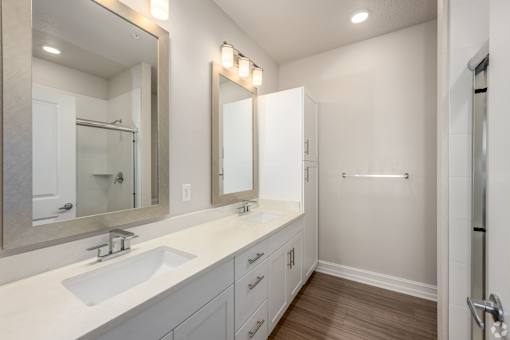 A bathroom with a sink, mirror, and wooden floors.