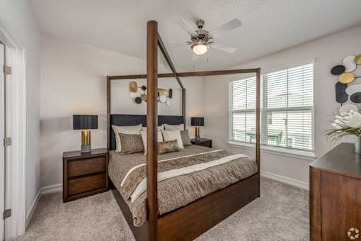 A bedroom with a four poster bed, two lamps, and a ceiling fan.