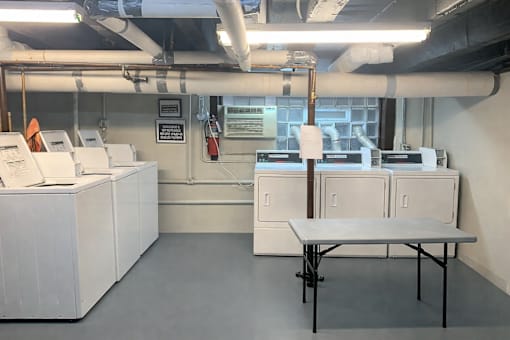 A room with a table, cabinets, and pipes.