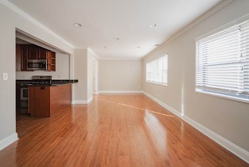 A spacious room with wooden floors and a kitchen area.