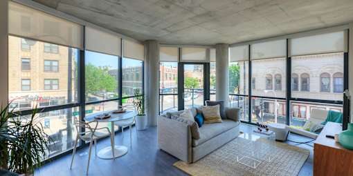 A living room with a couch, chairs, and a table with a plant in it.