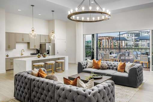 A modern living room with a grey tufted sofa and a chandelier.