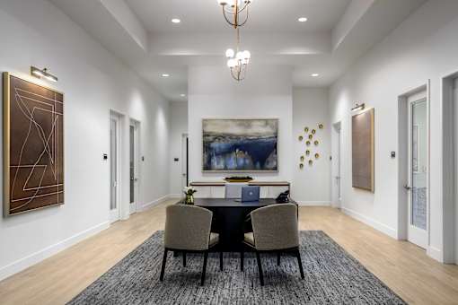 A dining room with a table set for two and a large painting on the wall.