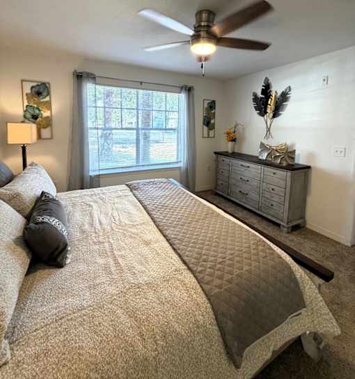 A bedroom with a large bed and a ceiling fan.