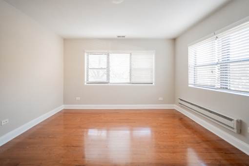 A room with wooden floors and a window with blinds.