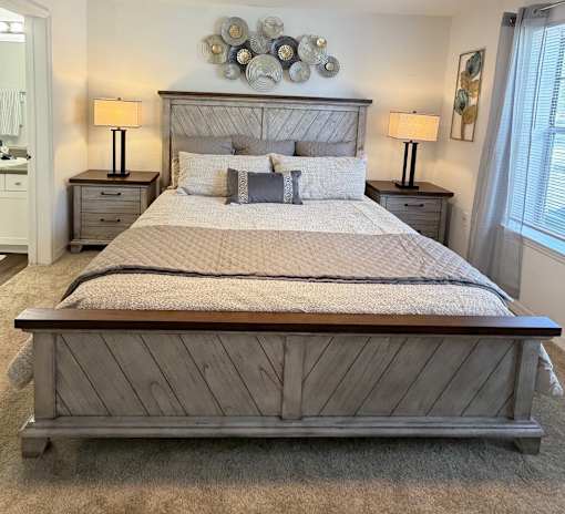 A bed with a wooden headboard and footboard with a white comforter and pillows.