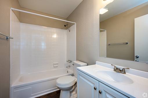 A white bathroom with a toilet, sink, and bathtub.
