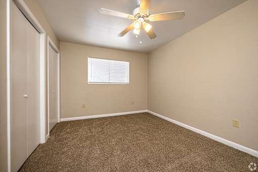 A room with a ceiling fan and carpeted floor.