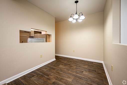 A room with wooden flooring and a chandelier hanging from the ceiling.