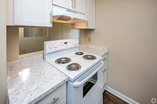 A white stove top oven with four burners and a white oven underneath it.