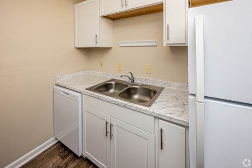 A kitchen with white cabinets and a marble countertop.