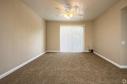 A room with a ceiling fan and carpeted floor.