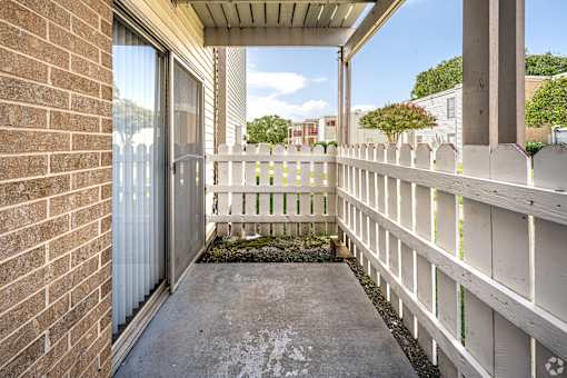 A small balcony with a white railing and a brick wall.