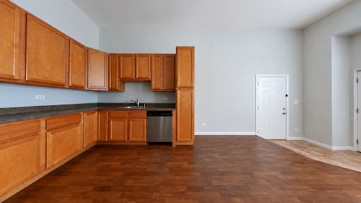 A kitchen with wooden cabinets and a trash can.