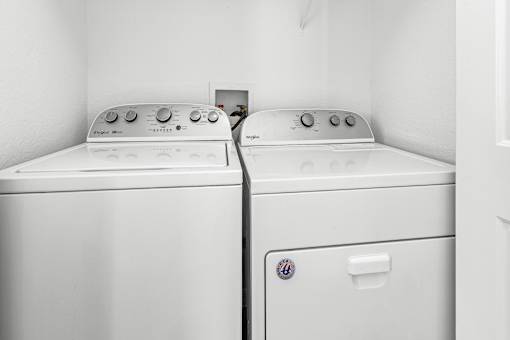 Two white front loading washing machines in a laundry room.