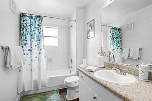 A white bathroom with a toilet, sink, and shower.
