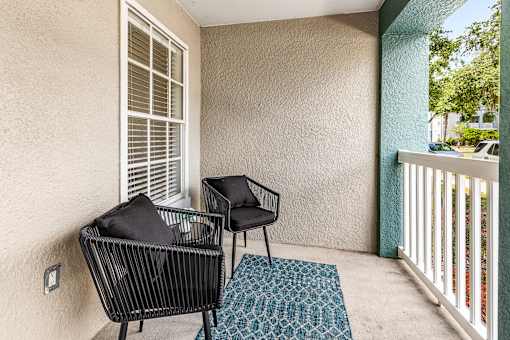 A patio with a black chair and a black couch.