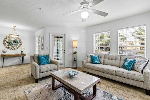 A living room with a grey couch, a coffee table, and a ceiling fan.