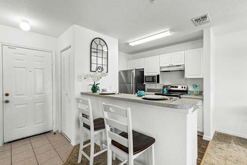 A kitchen with white cabinets and a countertop with a sink and a microwave.