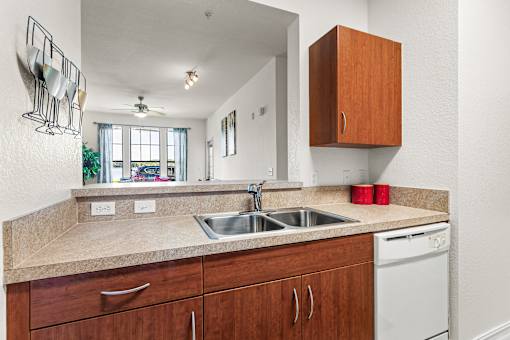 A kitchen with a white dishwasher and brown cabinets.