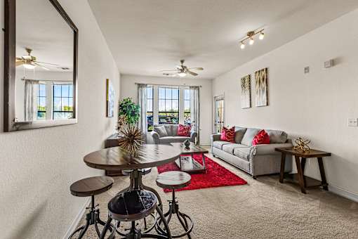 A living room with a grey couch, a round table, and a red rug.