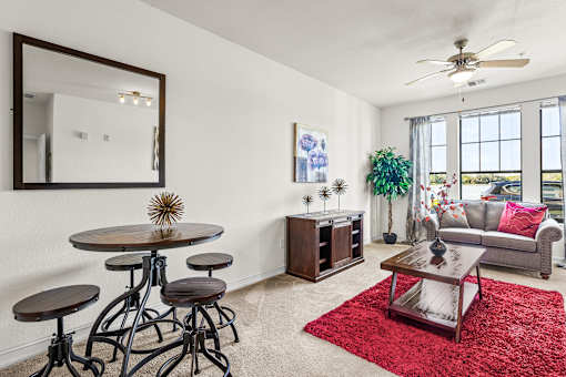 A living room with a round table and a red rug.