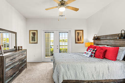 A bedroom with a bed, dresser, and ceiling fan.
