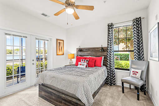 A bedroom with a bed, chair, and a ceiling fan.