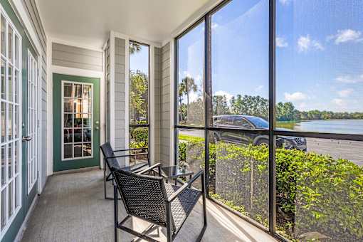 A balcony with a chair and a table overlooking a body of water.