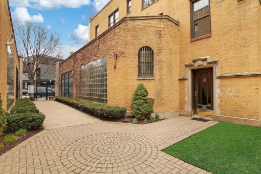 the exterior of a brick building with a walkway and grass