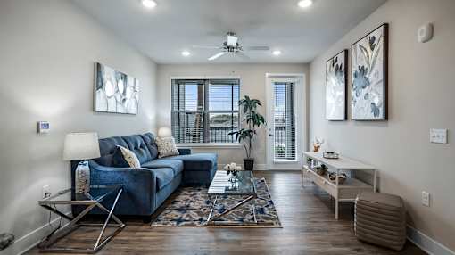 A living room with a blue couch and a rug.