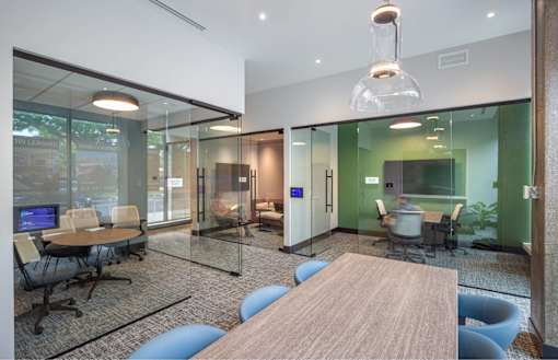 A modern office space with glass walls and a wooden table.