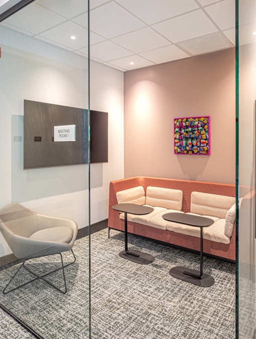 A glass wall separates a meeting room from a hallway.
