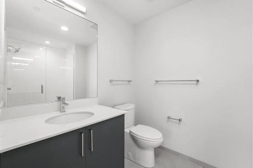 A white bathroom with a toilet, sink, and mirror.
