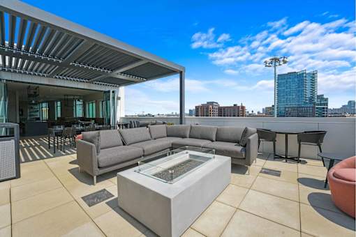 A modern outdoor living space with a large grey sofa and a glass coffee table.