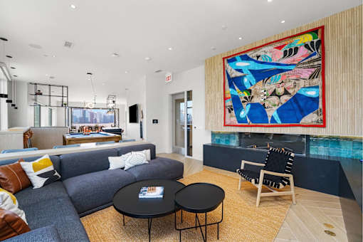 A living room with a grey couch, a black coffee table, and a large abstract painting on the wall.