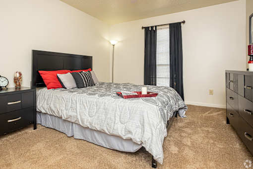 A bedroom with a bed, nightstand, and window.