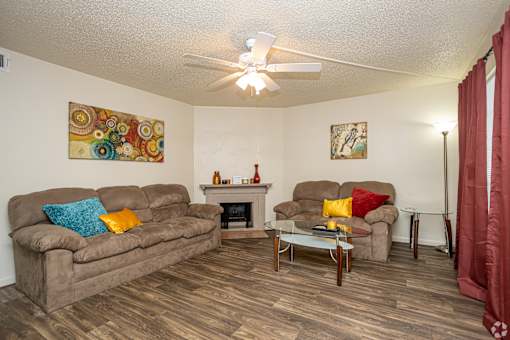 A living room with a brown couch, a fireplace, and a painting on the wall.