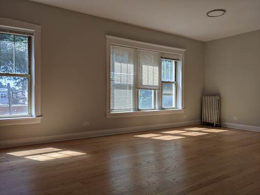 A room with wooden floors and two windows.