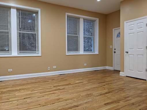 A room with wooden floors and two windows.
