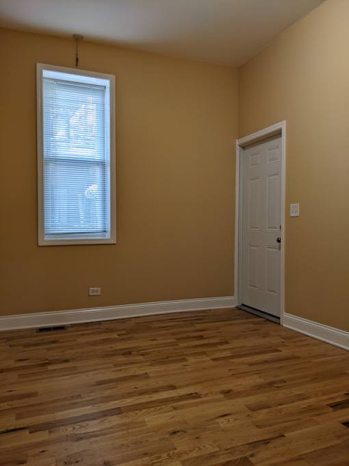 A room with a white door and a window with blinds.