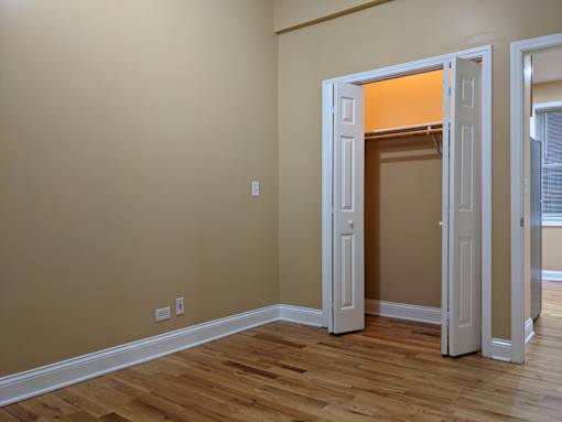 A room with a white door and wooden flooring.