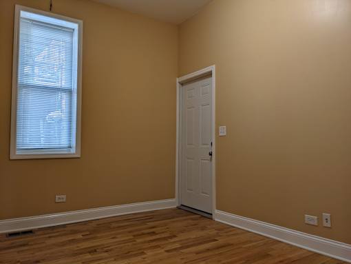 A room with a white door and a window with blinds.