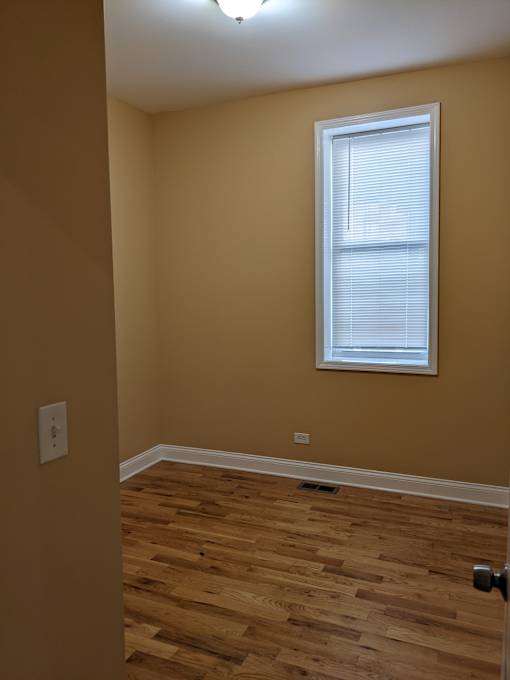 A room with a window and wooden flooring.