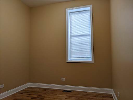 A room with a window and wooden flooring.