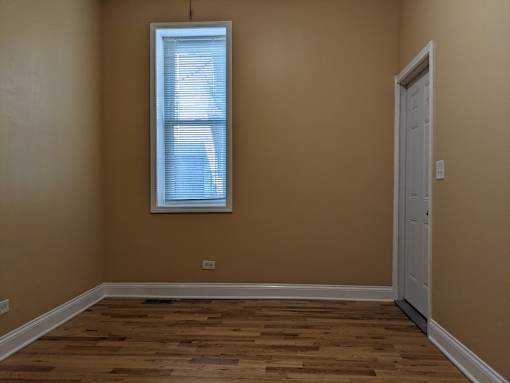 A room with a wooden floor and a white door.
