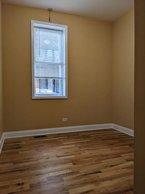 A room with a window and wooden flooring.