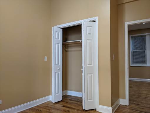 A white door with a shelf is open in a room.