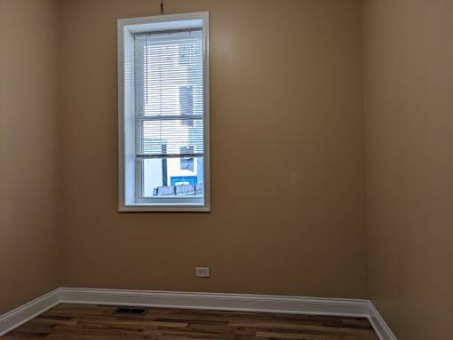 A room with a window and wooden flooring.